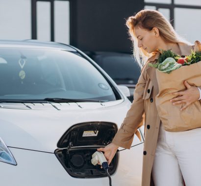 Woman with food shopping bags charging electric car